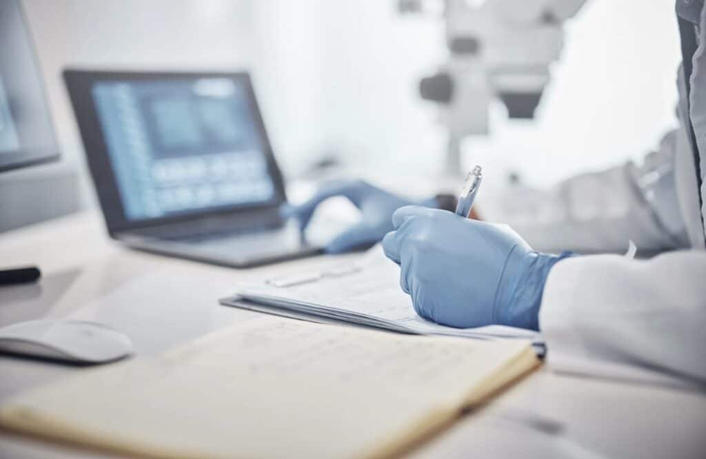 doctor's hands in front of a computer taking notes